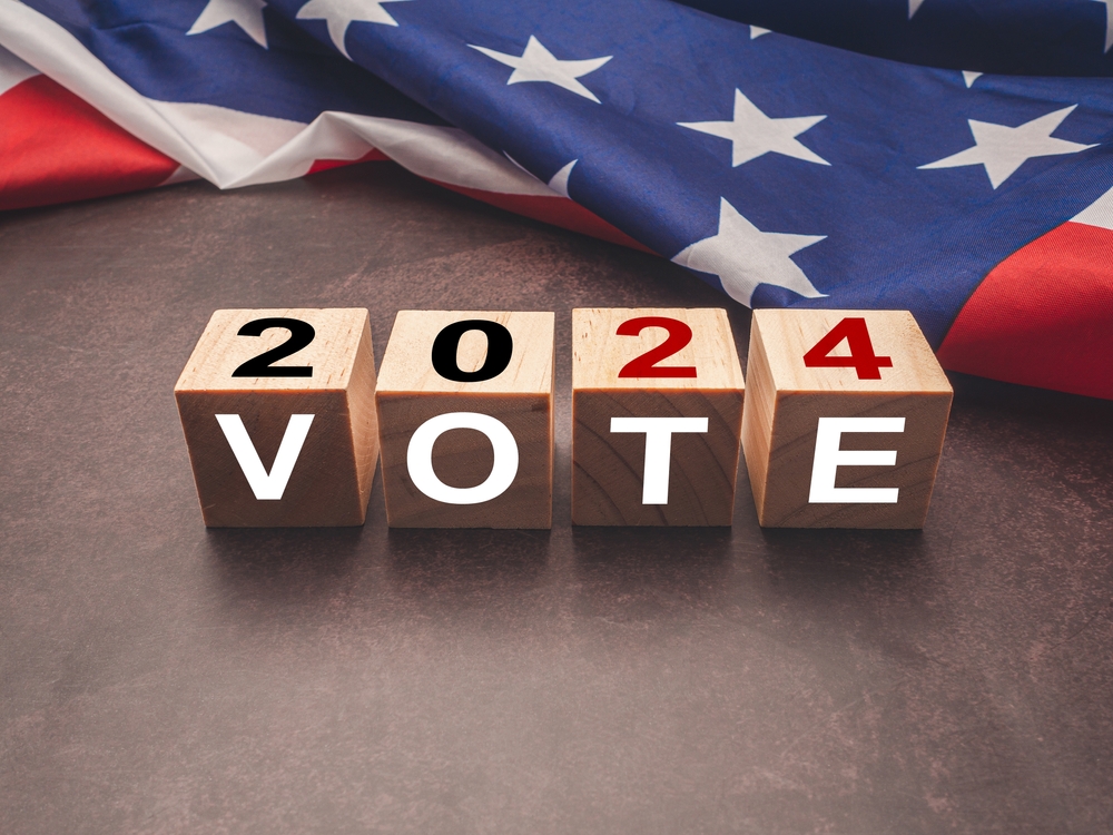 Wooden cubes with text VOTE and 2024 over the American flag background