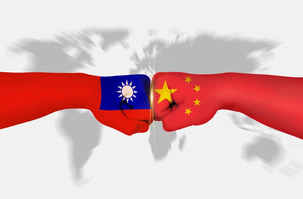 China and Taiwan with flags painted on their hands punch each other on a light gray world map background