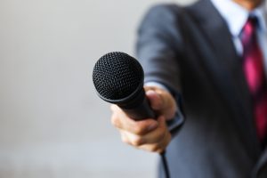 Man,In,Business,Suit,Holding,A,Microphone,Conducting,An, interview