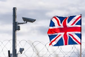 Flag,Of,The,United,Kingdom,With,Surveillance,Camera,And,Barbed